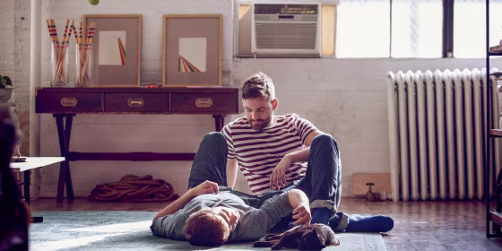 Couple laying on the carpet with their cat, with a window AC unit behind them. These are the best affordable window air conditioners in 2021. Shop the best window air conditioners from LG, GE, Whirlpool, Toshiba and more.