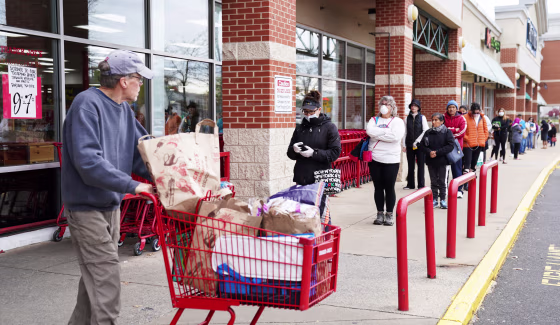 A shopper passes near a self-distancing queue outside Trader Joe's in Bailey's Crossroads, Va., on March 31, 2020.