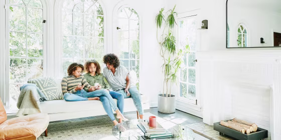 Mother and daughters sitting in living room watching video on smart phone