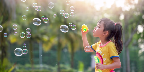 Little girl playing with bubbles outside