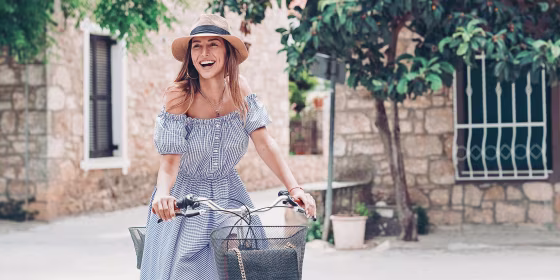 Woman with a bicycle, wearing a hat and blue dress