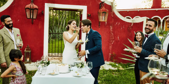 Laughing bride feeding cake to groom during outdoor wedding reception. These are the best wedding cake toppers to try in 2021. Shop custom and unique wedding cake toppers from Etsy, Hobby Lobby, Michaels and more.
