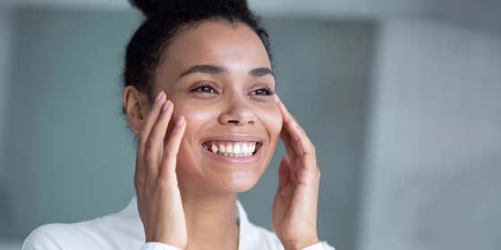 Woman touching her face while looking in the mirror