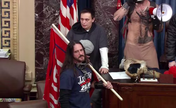 Image: Paul Allard Hodgkins carries a large red \"Trump 2020\" flag inside the Senate chamber during the Capitol riot on Jan. 6.