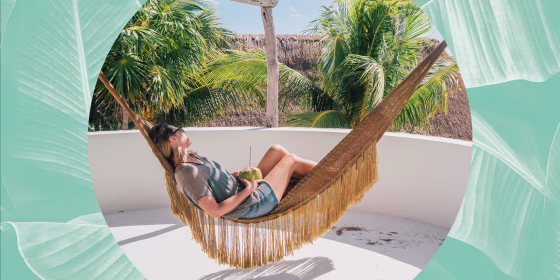 Woman relaxing in a Hammock, looking at the view, holding a coconut