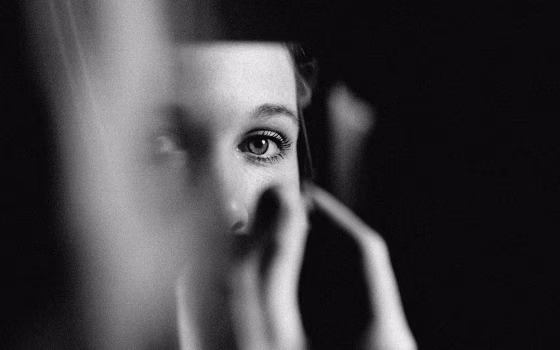 Image of a woman's eyes in a sliver of mirror.