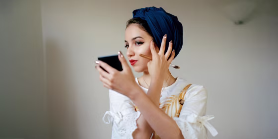 Portrait of young muslim woman applying make up