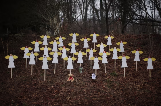 Twenty-seven wooden angel figures are seen placed in wooded area beside road near Sandy Hook Elementary School for victims of school shooting in Newtown, Connecticut