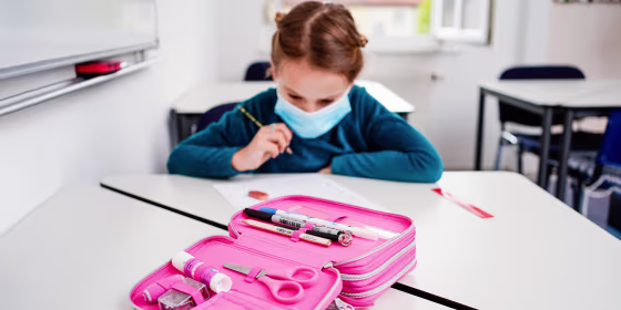Eight-year-old Anna sits at a table in front of an exercise sheet during a German lesson, with a pink pencil case in front of her