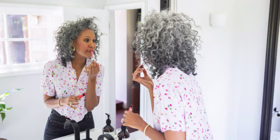 Beautiful Woman putting on her makeup in a bathroom mirror