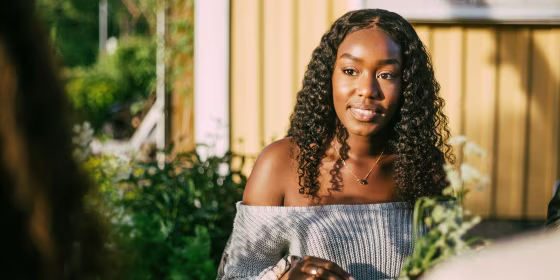 Smiling female looking at friend while sitting in yard