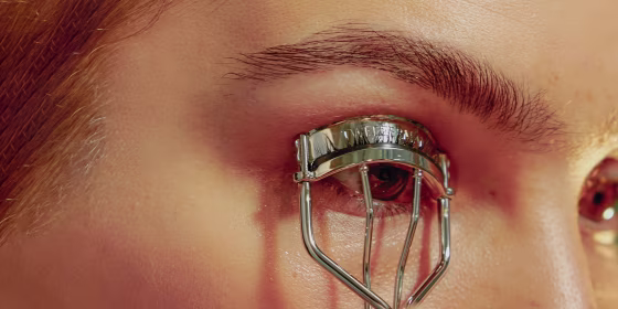 Portrait of Young Confident Woman Curling Her Eyelashes