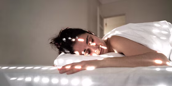 Woman Lying On Bed At Home, with light shining on her face
