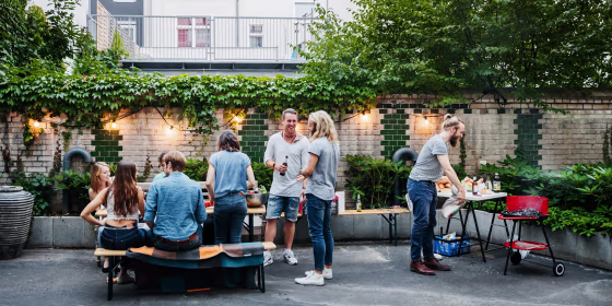 A young, stylish group of friends outside in a city backyard, drinking and cooking on a summer day