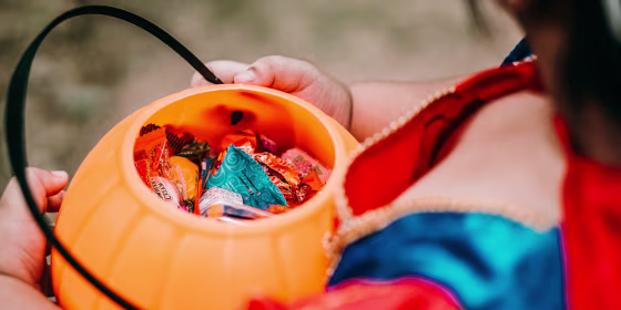Little girl in costume holding trick or treat candy