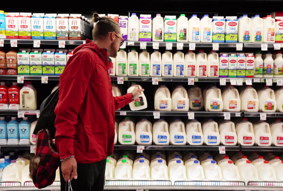 Image: A customer takes a gallon of milk for sale at a grocery store in Salt Lake City on Oct. 21, 2021.