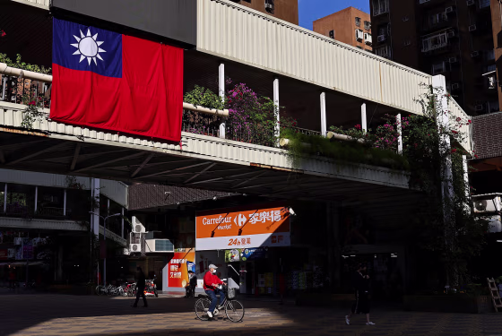 Image: A man cycles past a Taiwan flag in Taipei
