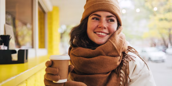 Woman in winter hat and scarf holding coffee cup