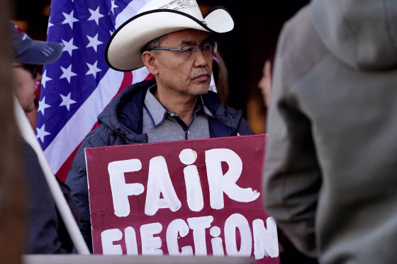 Image: A protestor holds a placard as Arizona electors gather to cast their votes for the U.S. presidential election, in Phoenix