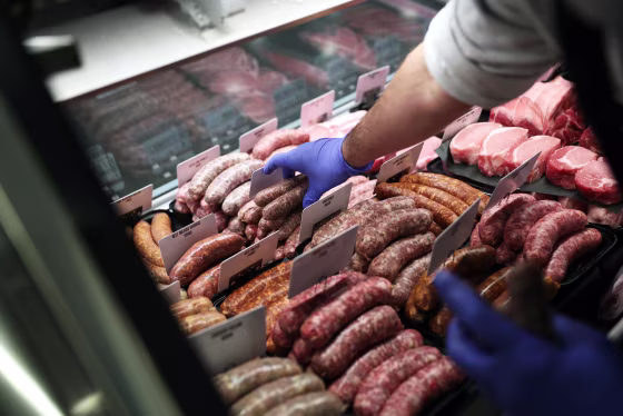 A worker places pork sausages into a display case at Baron's Quality Meats in Castro Valley Marketplace in Castro Valley, Calif., on Jan. 12, 2022.