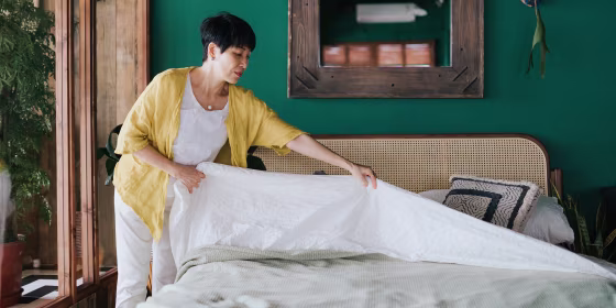 Senior Asian woman doing her morning routine, making up her bed at home