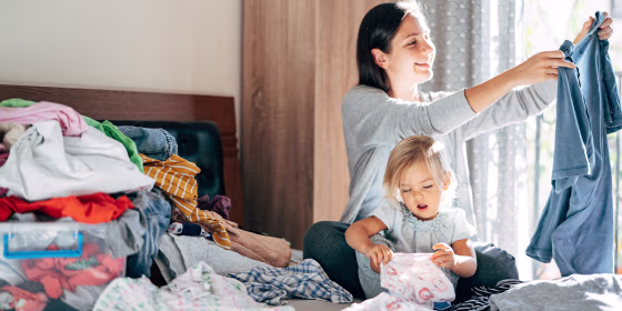 Smiling Mother And Daughter Folding Clothes At Home