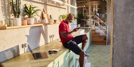 Businessman text messaging on smart phone while sitting at home