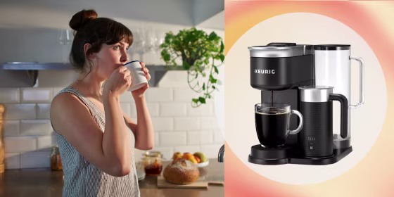 A woman standing in her kitchen drinks from a mug and the Keurig Cafe
