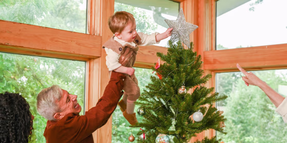 A Little boy putting up a Christmas Tree topper