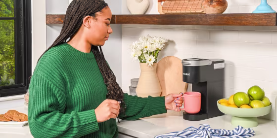 Woman holding cup under Keurig