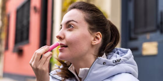 Woman putting on chapstick, outside