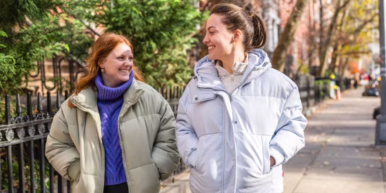 Two woman wearing puffer jackets outside