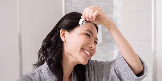 Woman putting serum on her face in a bathroom