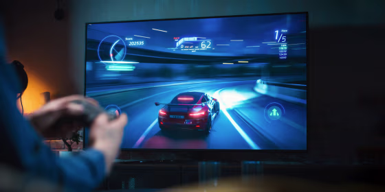 Close Up on Man's Hands at Home, Sitting on a Couch in Stylish Loft Apartment and Playing Arcade Car Video Games on Console. Male Using Controller to Play Street Racing Drift Simulator.