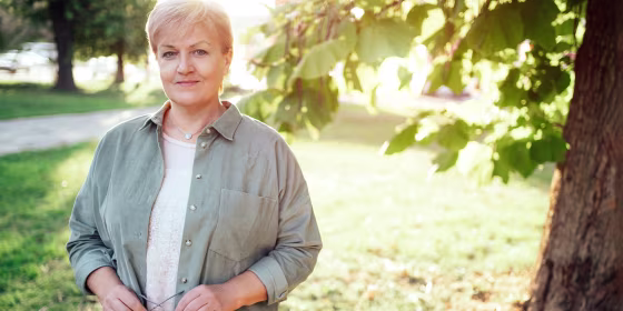 Senior blonde woman is resting in the city park. She is wearing modern casual clothing