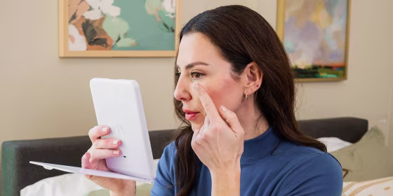 Woman touching her face while looking in her mirror
