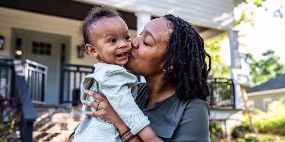 Mother holding toddler in front of new home