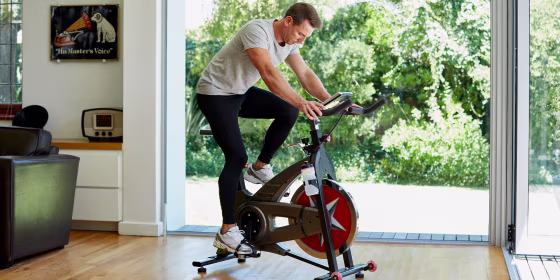 Full length of man working out on exercise bike at home