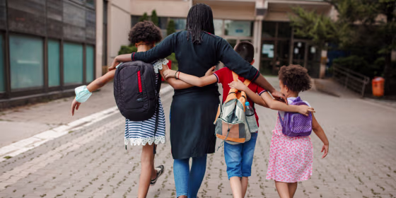 Black woman taking three kids to school