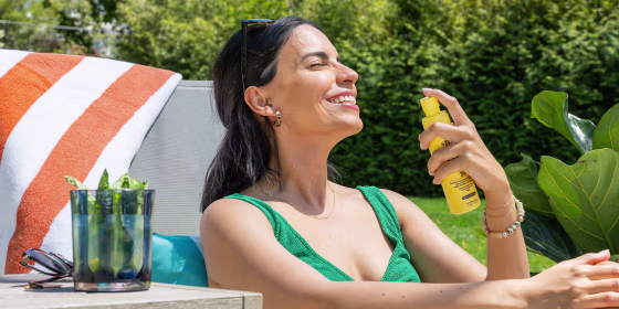 Woman spraying sunscreen on her face