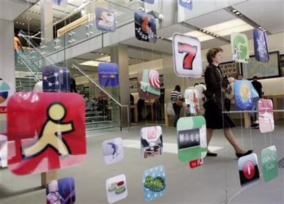 A woman walks past icons for Apple applications at the company's retail store in San Francisco, California in this April 22, 2009 file photo.