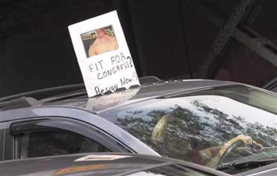 A man holds a sign out of their car calling for representative Anthony Weiner to resign, outside Weiner's residency at the Queens borough of New York