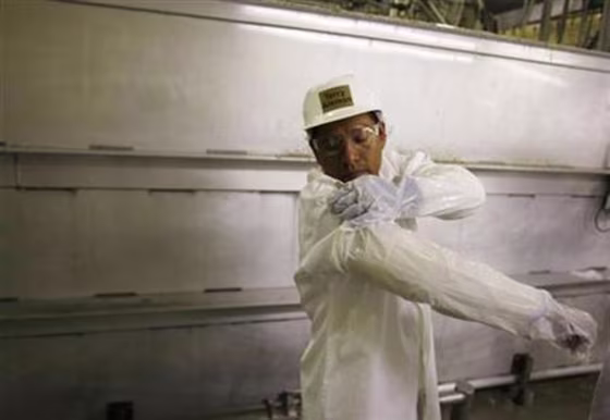 A worker fastens a plastic cover over a Kevlar sleeve made to protect his arms as he returns from a break at the West Liberty Food processing plant in West Liberty