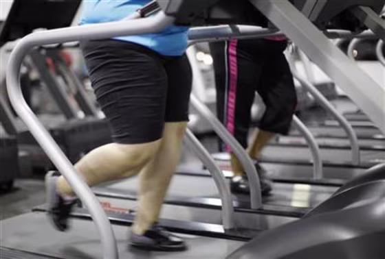 Jazmine Raygoza, 17, (L) jogs on a treadmill  during a workout at a gym in Englewood