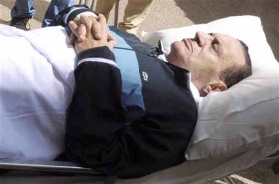 Former Egyptian president Hosni Mubarak lies on a bed while being taken to the courtroom at the police academy in Cairo