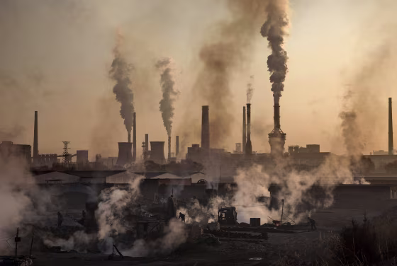 Image: Smoke billows from a large steel plant as a Chinese laborer works at an unauthorized steel factory in Inner Mongolia, China.
