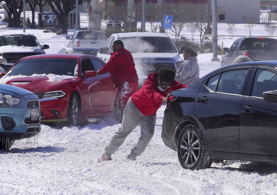 Image: People push a car free after spinning out in the snow Monday, Feb. 15, 2021 in Waco, Texas