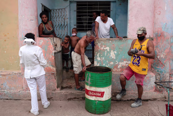 Image: A nurse asks a family to go to a vaccination center in Havana
