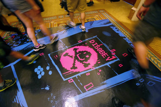 People walk past a floor graphic during the Def Con hacker convention in Las Vegas