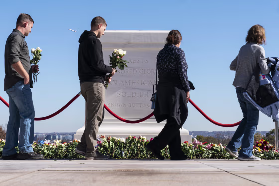 People walk to place flowers during a centennial commemoration event at the Tomb of the Unknown Soldier in Arlington National Cemetery on Nov. 9, 2021, in Arlington, Va.